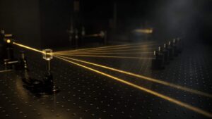 A luminous beam separating into several parallel paths inside a dim physics laboratory.